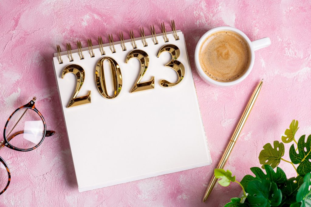 New year resolutions 2023 on desk. 2023 resolutions list with notebook, coffee cup